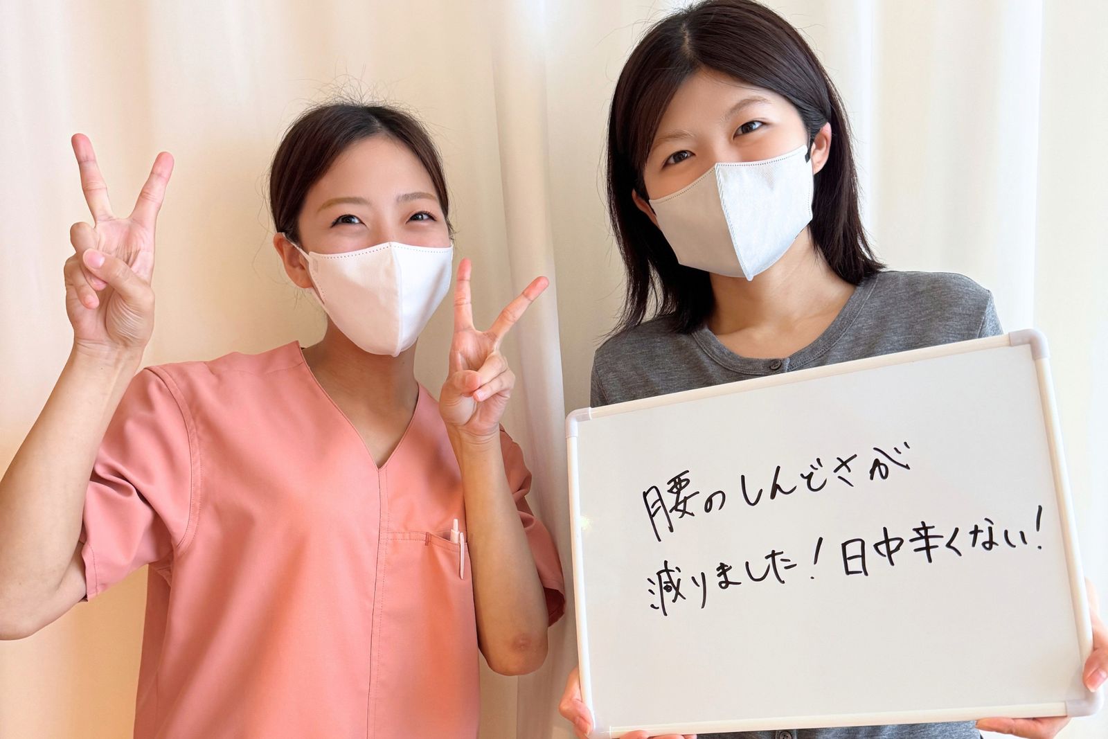 「腰のしんどさが減りました！日中辛くない！」と書かれたホワイトボードを持つ患者さまと担当鍼灸師
