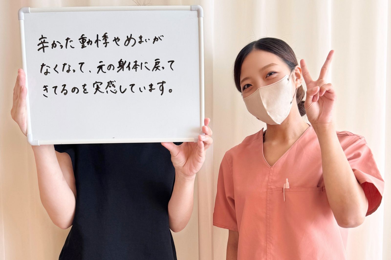 「辛かった動悸やめまいがなくなって、元の身体に戻ってきてるのを実感しています。」と書かれたホワイトボードを持つ患者さまと担当鍼灸師