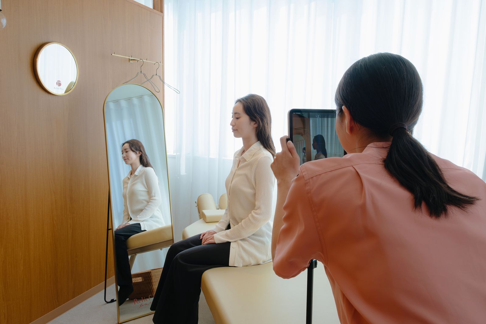 鏡の前に座った患者さまの姿勢を、タブレットで撮影して確認している様子
