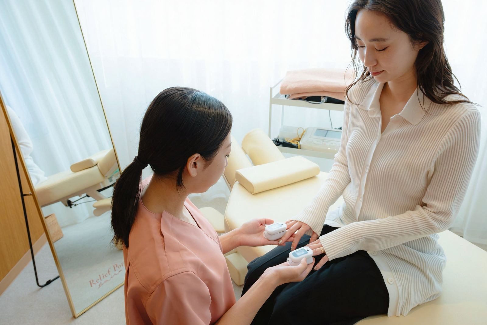 施術後、ベッドに座った患者さまに鍼灸師が説明している様子