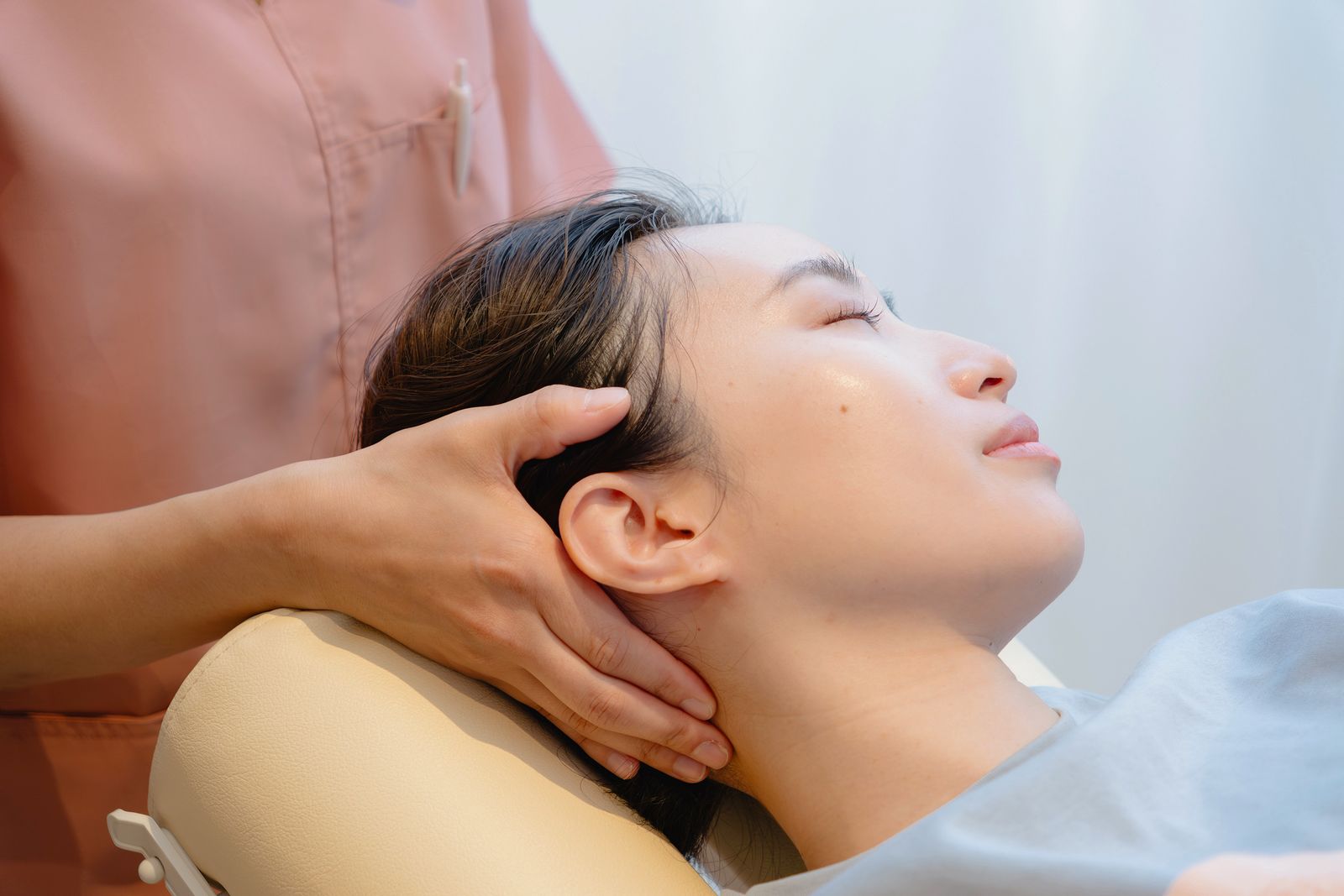 仰向けの患者さまの首と後頭部に手を添えて施術している様子