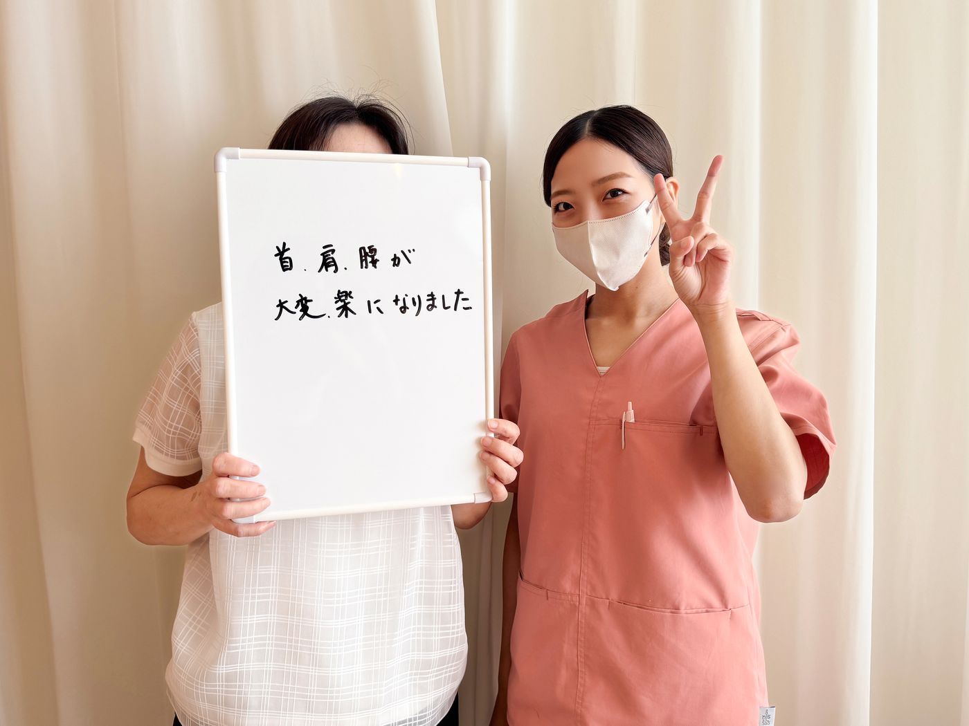 「首、肩、腰が大変楽になりました」と書かれたホワイトボードを持つ患者さまと鍼灸師