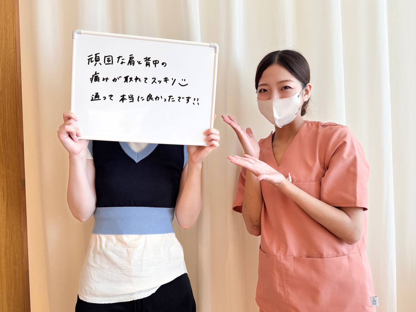 「頑固な肩と背中の痛みが取れてスッキリ 通って本当に良かったです！！」と書かれたホワイトボードを持つ患者さまと鍼灸師
