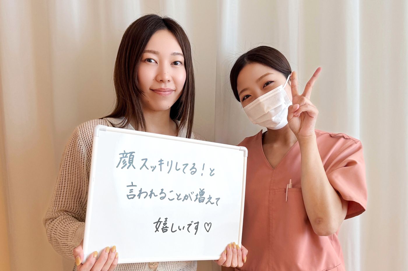 「顔スッキリしてる！と言われることが増えて嬉しいです」と書かれたホワイトボードを持つ患者さまと鍼灸師